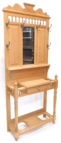 A pine hall stand in Victorian style, the raised back above spindle turned frieze and a rectangular mirror surrounded by six metal hooks, the base with a frieze drawer and recesses for umbrellas, lacking drip tray, 210cm H, 93cm W.