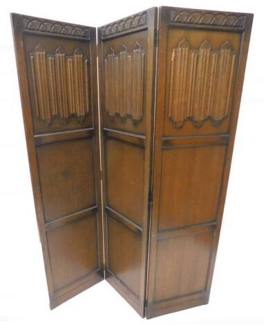 An oak three fold screen, with carved frieze and linen fold panels, each leaf 166cm x 46cm.