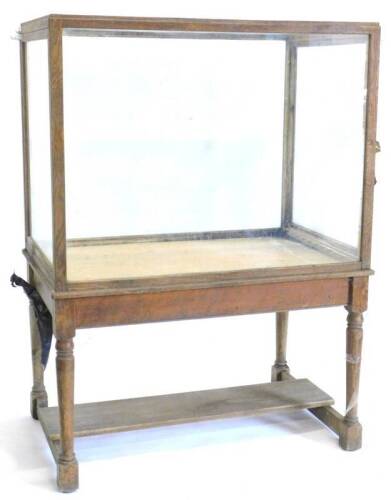 An oak and glazed museum type display cabinet, of rectangular form on turned supports with flat central stretcher, 168cm H, 125cm W, 79cm D.