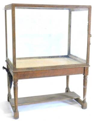 An oak and glazed museum type display cabinet, of rectangular form on turned supports with flat central stretcher, 168cm H, 125cm W, 79cm D.