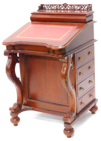 A mahogany Davenport in Victorian style, with a pierced gallery above a recess for pens, the concave slope inset with a red leatherette writing surface enclosing eight small draws with brass handles, on cabriole shaped supports with four drawers to each s