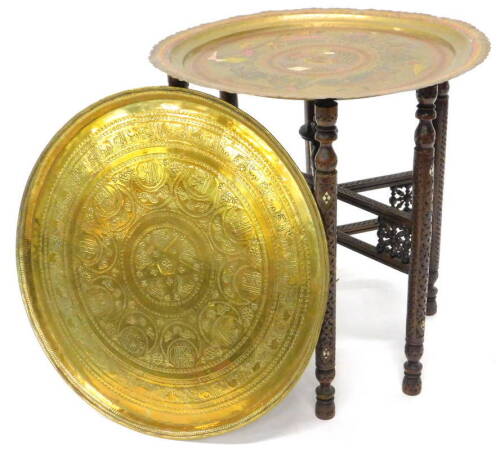 An unusual Indian brass tray on stand, the tray engraved with a procession of elephants, figures, etc., surrounding a central scene of a noble man with attendants, picked out in pink, gold and red, within a leafy border, the folding stand inlaid in mother