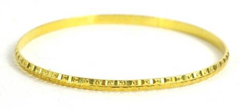 A bangle, of etched and raised circular design, mark to inner band DHAKAN, 22c, 10.7g.