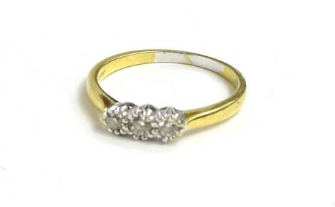 An 18ct gold three stone diamond ring, set with three illusion set tiny diamonds, with pierced ring head, 3.1g.