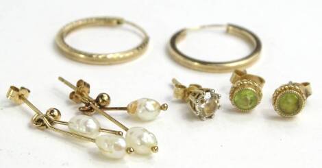 Three pairs of earrings, to include a pair of 9ct gold peridot set stud earrings, a pair of 9ct gold hoop earrings, and a pair of 9ct gold cultured pearl two strand drop earrings, and another loose earring. (7)