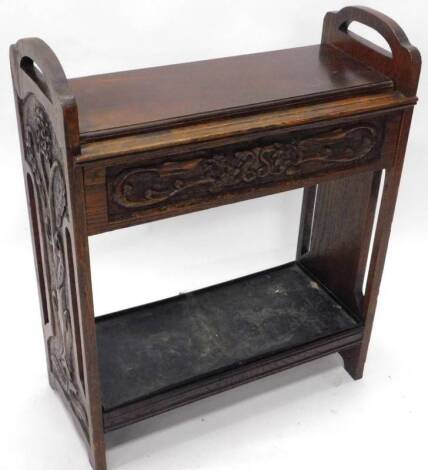 An early 20thC oak umbrella stand, with two side handles and two recesses and a tin drip tray, 82cm W.