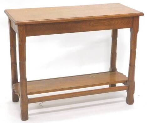 An oak side table in Arts and Crafts style, the rectangular top with a moulded edge on faceted supports, with rectangular flat under tier, 98cm W, 77cm H, 44cm D.