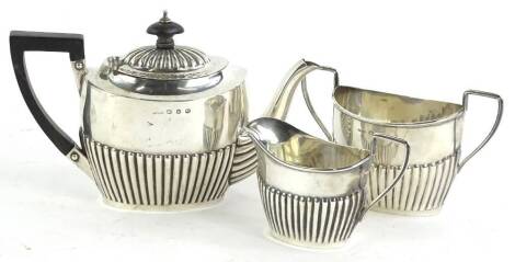 A George V silver bachelors three piece tea set, with part fluted decoration, the teapot with ebonised handle and knop, Birmingham 1911, 12¾oz gross.