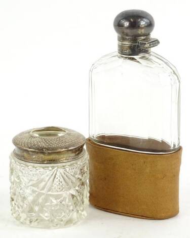 An Edwardian cut glass and silver mounted spirit flask, with associated leather base, Birmingham 1906, and a cut glass and silver hair tidy. (2)