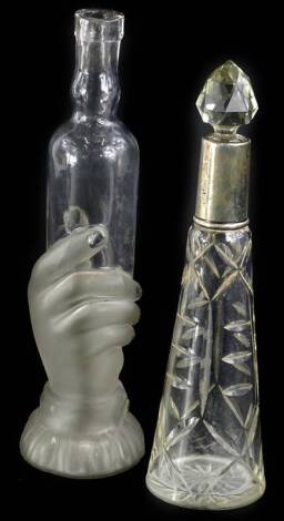 A cut glass scent bottle, with silver collar and faceted stopper, marks indistinct, 22cm H, and a Victorian bottle, the opaque part frosted base modelled in the form of a hand, 24cm H. (2)