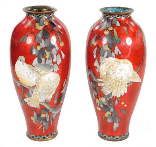 A pair of Japanese red ground cloisonné baluster vases, decorated with doves in foliage, 30cm H. (both AF)