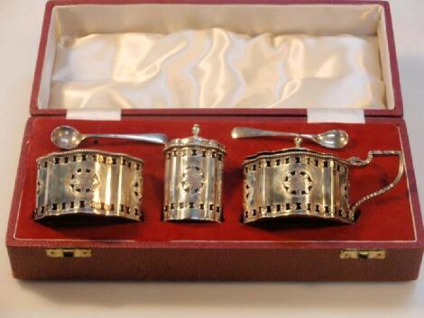 A silver cruet set of cartouche shape with paterae pierced bodies