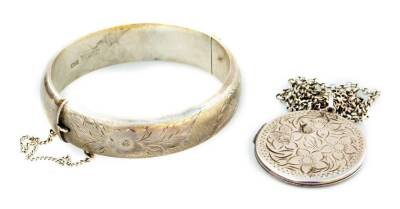 Two items of silver jewellery, to include a silver locket and chain, with floral engraving to front, and a silver bangle. (2, AF)