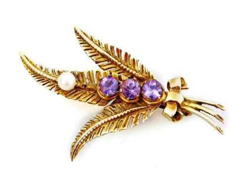 A Prince of Wales feather brooch, set with three amethyst stones and a single seed pearl, and bow to base, yellow metal, marked 9ct, 4.5cm W.