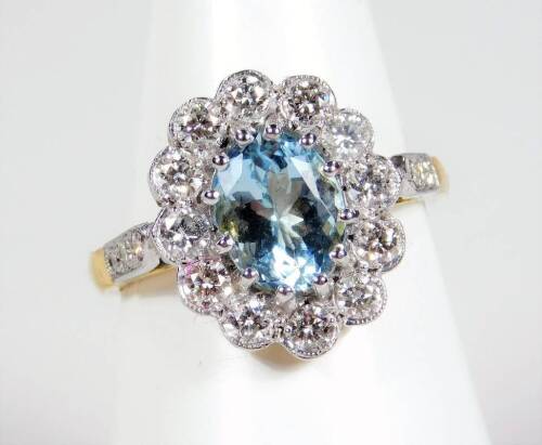 An 18ct gold aquamarine and diamond cluster ring, the cluster with central aquamarine 8.2mm x 6.2mm x 4.4mm, surrounded by ten round brilliant cut diamonds, each less than 0.1cts, in rub over setting, in platinum, on a yellow metal band, 5g all in.