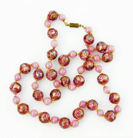 A pink Venetian glass beaded necklace, with two design pink beads, one elaborately decorated, on string necklace with a gold plated clasp, 69cm L overall.