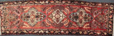A Tabriz runner, in red and cream, 310cm x 95cm.