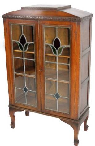 An early 20thC Arts & Crafts oak display cabinet, with partially coloured lead glazed doors, on shaped legs and block feet, 125cm H, 72cm W, 32cm D.