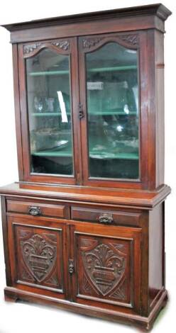 A late 19thC walnut bookcase, the shaped cornice raised above two glazed doors, with a fitted interior, the sub section with two frieze drawers above a double cupboard, each carved with shields, on bracket feet, 211cm H, 120cm W, 46cm D.