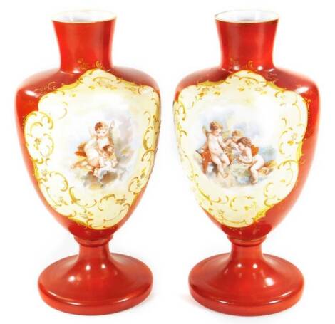 A pair of early 20thC continental glass vases, each overlaid with cherubs, with scroll highlights on a orange ground, 31cm H. (2)