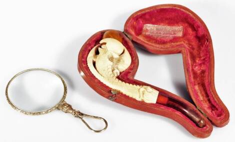 An early 20thC magnifying glass, with hook end and plain circular body, unmarked, and a early 20thC meerschaum pipe carved with claw, in fitted case. (2)