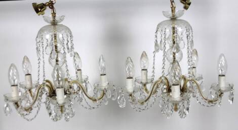 A pair of metal framed cut glass and crystal five branch chandeliers, with domed floral tops, turned centre stems, arched branches and mock candle shades, with chain fittings, 49cm H. (2)