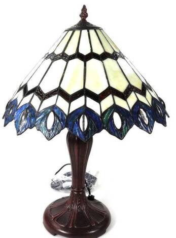 An as new table lamp, with Tiffany style shade, with repeat peacock feather border predominately in blue, cream and red, 55cm H.