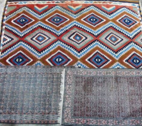 A Chinese rug, in a repeat geometric pattern, predominately in blue and peach, another similar, 153cm x 76cm, and a further in South American rug in geometric pattern. (3)