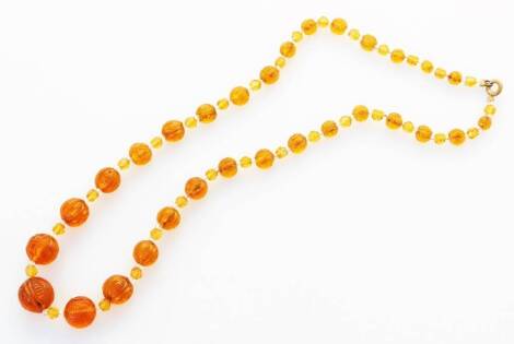 An Eastern style beaded necklace, with carved orange and white beads, on white string, with brass clasp, 47cm long overall.