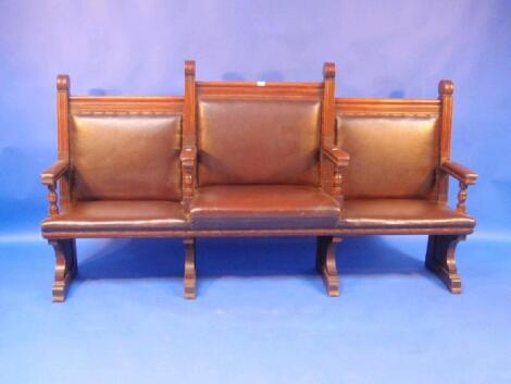 An Edwardian oak Magistrates bench with brown rexine studded upholstery