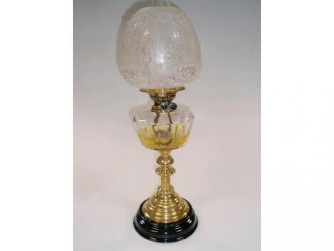 A 19thC oil lamp, with a clear cut glass reservoir on a brass candlestick