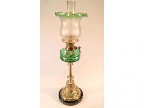 A 19thC oil lamp, with a clear emerald green glass reservoir, over a swept