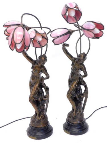 A pair of late 20thC French bronzed resin lamp bases, each with stained glass tulip shaped shades, 70cm H.