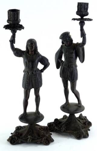 A pair of continental bronze patinated cast iron candlestick figures, each wearing historical dress on a circular base, with three feet, possibly Russian, 37cm H.