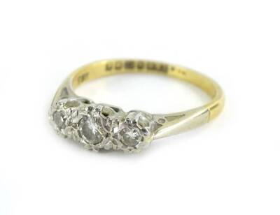 An 18ct gold and platinum three stone diamond ring, set with three illusion set tiny diamonds, on raised platinum setting, with pierced shoulders, on a yellow metal band, ring size K½, slightly misshapen, 2.5g all in.