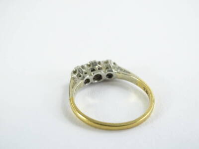 An 18ct gold and platinum three stone diamond ring, set with three illusion set tiny diamonds, on raised platinum setting, with pierced shoulders, on a yellow metal band, ring size K½, slightly misshapen, 2.5g all in. - 2