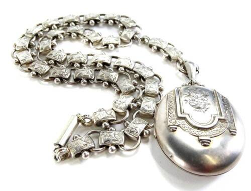 A silver locket and chain, the locket with floral scroll design to front, and brushed white metal back, on an Eastern style neck chain, with design of leaves, 53.9g all in, the locket 5cm H x 4cm W