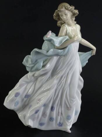 A Lladro porcelain figure of a lady, with a flowing dress, holding a bird, 31cm H.