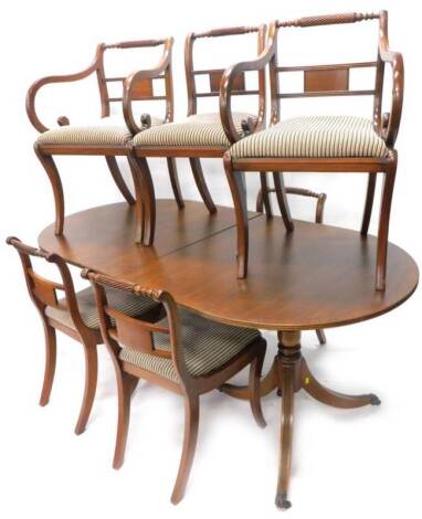 A Reprodux mahogany dining room suite, comprising a Regency style two pillar table with one leaf, the top 88cm x 219cm overall, and six matching sabre leg chairs. The upholstery in this lot does not comply with the 1988 (Fire & Fire Furnishing) Regulation