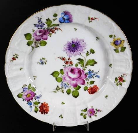 An 18thC continental porcelain plate, moulded, shaped and decorated with large flowers and groups within a gilt rim, crossed sword mark in underglaze blue, c1780, 24cm Dia.