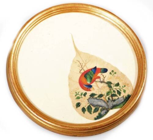 A 19thC waxed leaf, painted with exotic bird on a tree bough with flowers beyond, predominately in yellow, red and green, glazed and framed, 22cm Dia.