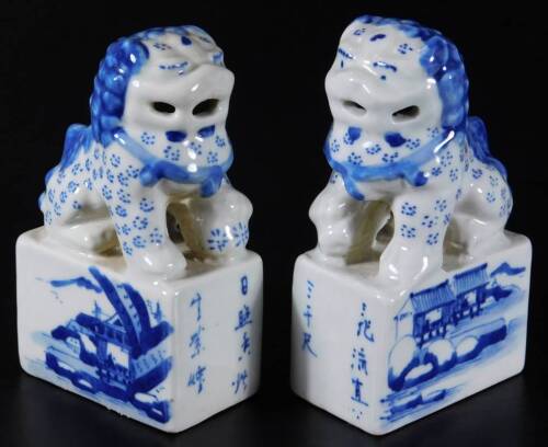 A pair of 20thC blue and white porcelain dog of fo seals, each decorated with figures and pagoda, with script to the front, with seal marks, 11cm H. (2)