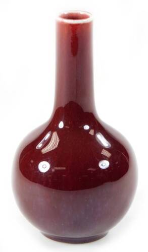 A Chinese porcelain sang de boeuf bottle vase, in deep red, with cylindrical stem and bulbous body, on circular foot, blue seal mark beneath, 17cm H.