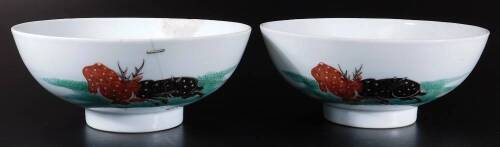 A pair of 19thC oriental porcelain bowls, each of circular form, on circular feet, polychrome decorated with stag and buffalo fighting, predominately in green, black and brown, double circle marks beneath, 19cm H. (2, AF)