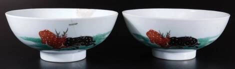 A pair of 19thC oriental porcelain bowls, each of circular form, on circular feet, polychrome decorated with stag and buffalo fighting, predominately in green, black and brown, double circle marks beneath, 19cm H. (2, AF)