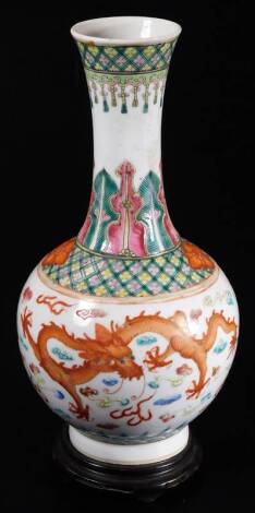 An 18thC Qianlong Chinese porcelain bottle vase, with inverted stem and bulbous body, decorated with five claw dragons, flowers and a repeat geometric banding, predominately in orange, green and yellow, on a circular foot, six character mark beneath, 24cm