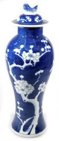 A 20thC Chinese porcelain baluster vase and cover, with compressed lid and stem, the inverted circular body decorated with a repeat prunus pattern in blue and white, on a circular foot, double circle mark beneath, 33cm H.