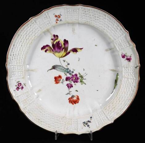 An 18thC continental porcelain plate, with a moulded lattice work border broken by handpainted flowers, the centre painted by further flowers, polychrome decorated predominately in red, yellow, purple and green, 25cm W.