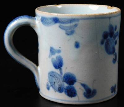 An 18thC Chinese blue and white export porcelain coffee can, the cylindrical body with decorative handle on a circular foot, Kangxi floral mark beneath, 6cm H. (AF) - 2