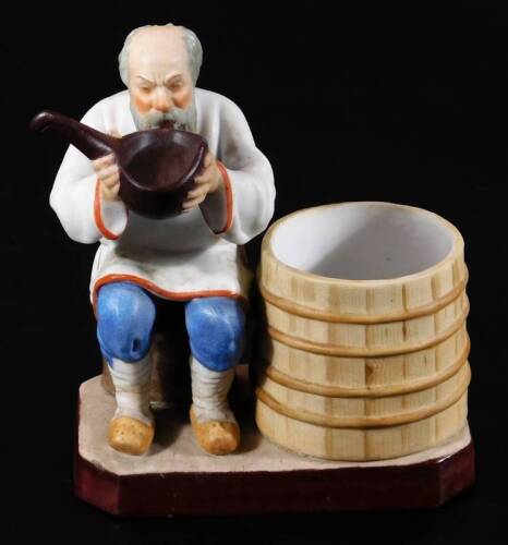A Russian Gardner bisque porcelain figure group, of a gentleman aside barrel drinking from a vessel, polychrome decorated predominately in blue, white and brown, impressed and printed marks beneath, 16cm H. (AF)
